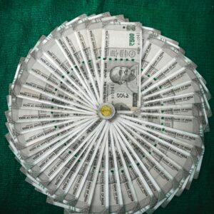 Top view of Indian Rupee notes arranged in a circular pattern on a green surface.